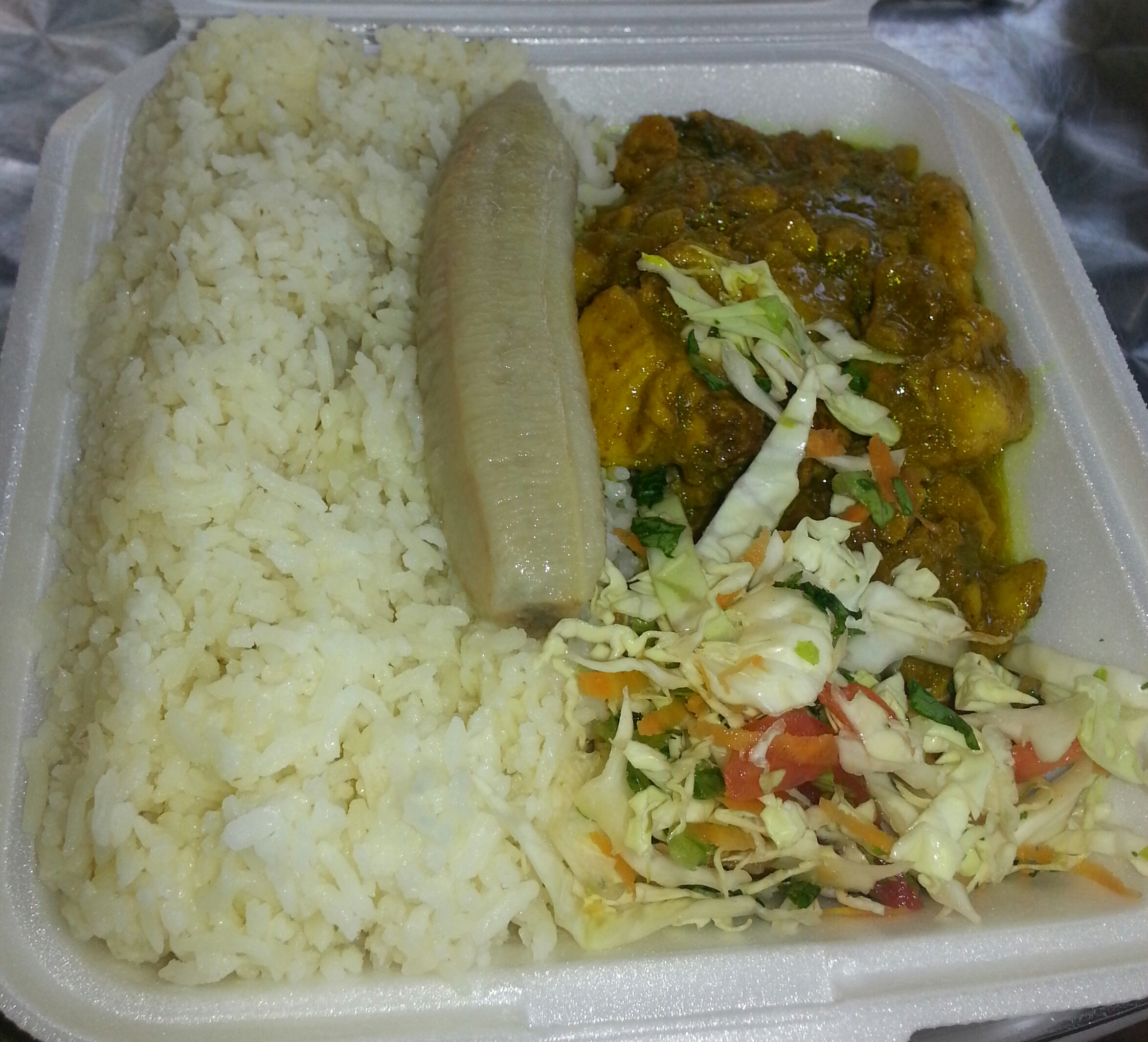 Curried goat with plain rice, boiled banana and raw vegetables